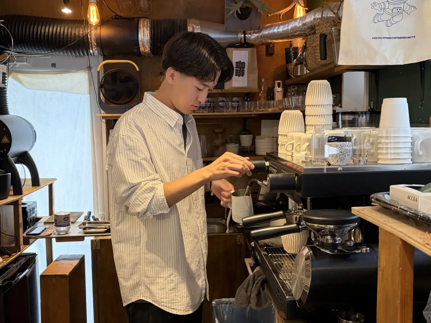 エスプレッソマシンの前でミルクを温める吉岡仁さん