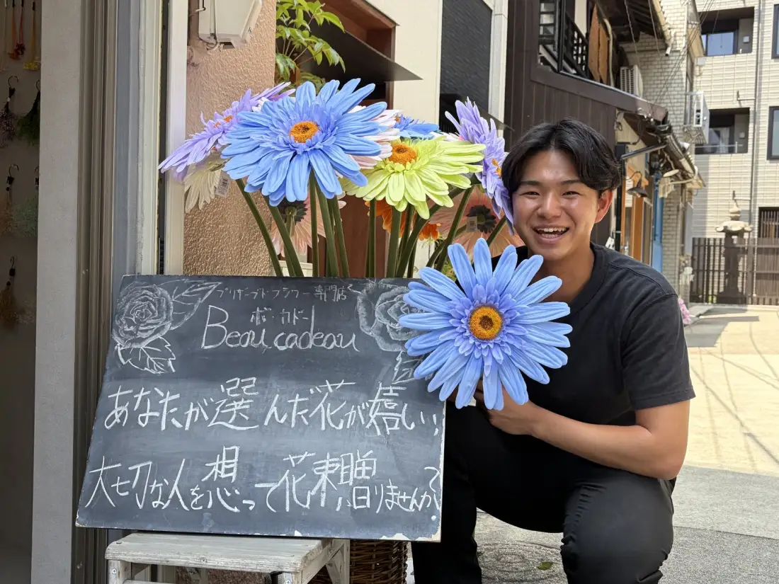 花屋 beau cadeau の店先で花を持つ爲本滉太さん
